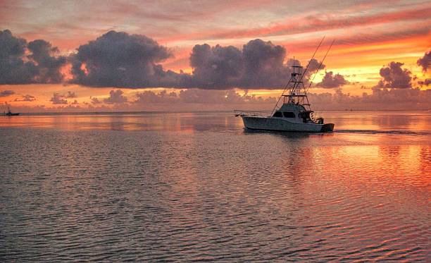 Fishing charter departs A fishing charter boat leaves very early in the morning from the Florida Keys fishing boat stock pictures, royalty-free photos & images