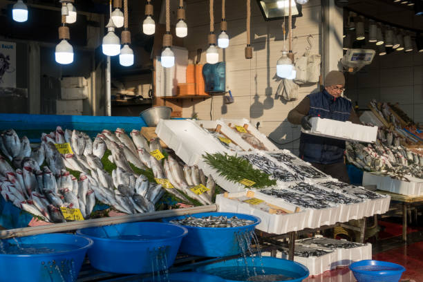 een visboer op zijn stand in de vismarkt in de buurt van galata bridge genaamd karakoy balik pasari - karaköy istanbul stockfoto's en -beelden