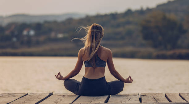 Fit and sporty young woman doing yoga next to the lake stock photo