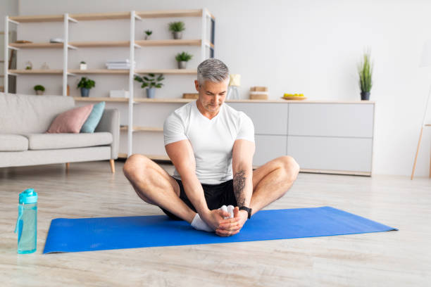 Fit mature man sitting in butterfly yoga pose to quit alcohol addiction