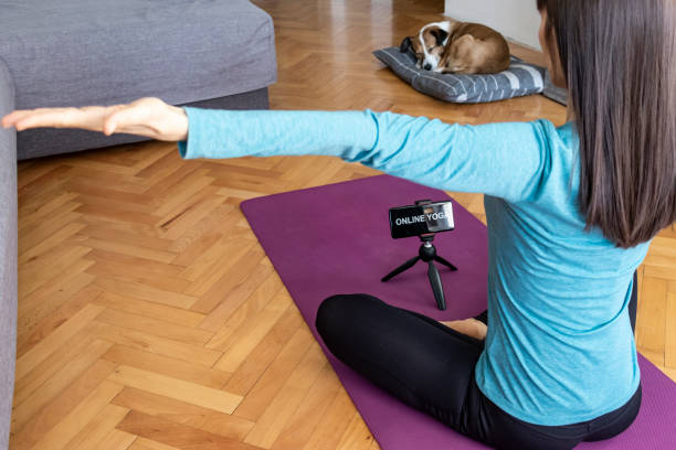 Fit woman doing yoga in living room, besides her dog stock photo