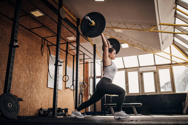 Fit woman training with weights in gym stock photo