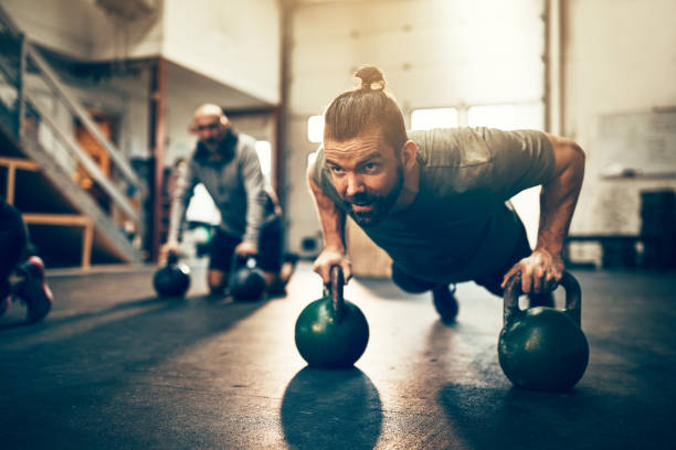 fit young man doing pushups with dumbbells at the gym picture