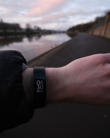 Nottingham, England - March,15,2021: Photo of a Fitbit being used to tell the time during a morning walk along Nottinghams' embankment. Fitbits and other fitness technology have become popular during the UKs' national lockdown as more people look to stay fit whilst gyms are closed.