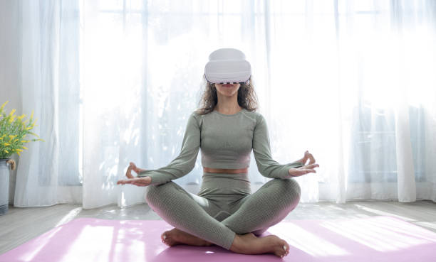 Fitness and lifestyle of the future, VR Yoga, Beautiful woman wearing virtual reality glasses while practicing yoga at home. stock photo