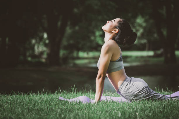 фитнес азиатская женщина делает йогу в парке - yoga стоковые фото и изображения