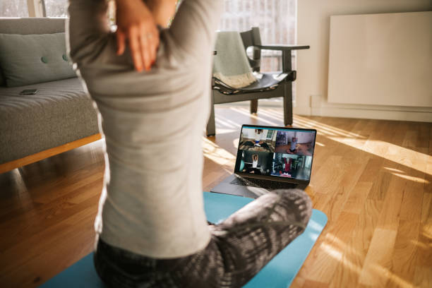 Fitness coach teaching yoga online to group of people Fitness coach teaching yoga online to group of people. Yoga trainer demonstrating yoga poses to students via video conference. yoga stock pictures, royalty-free photos & images
