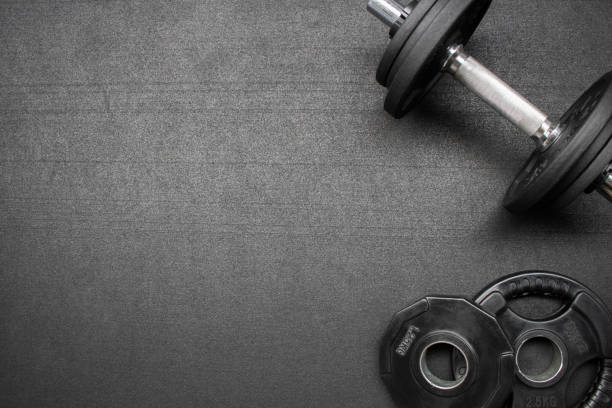 Fitness equipment on the floor at the gym Barbell and dumbbells on the floor at the gym. Top down view flat lay with bodybuilding equipment on a black background and empty space for text. Fitness, weight training or healthy lifestyle concept gym stock pictures, royalty-free photos & images