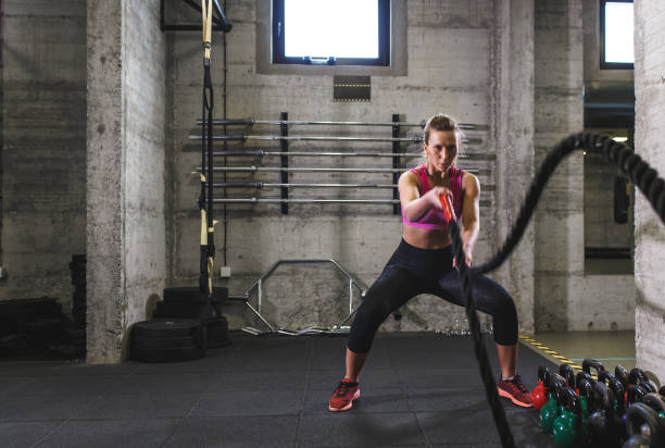 Fitness woman exercise in the gym with battle rope. Fitness woman exercise in the gym with battle rope. cross training stock pictures, royalty-free photos & images