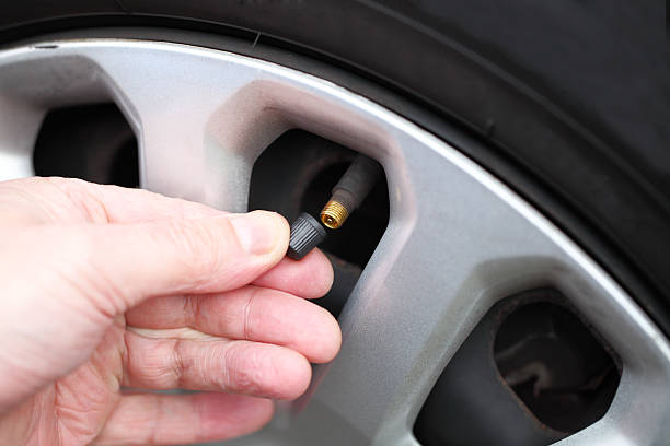 fitting cap to air valve on car tyre stock photo