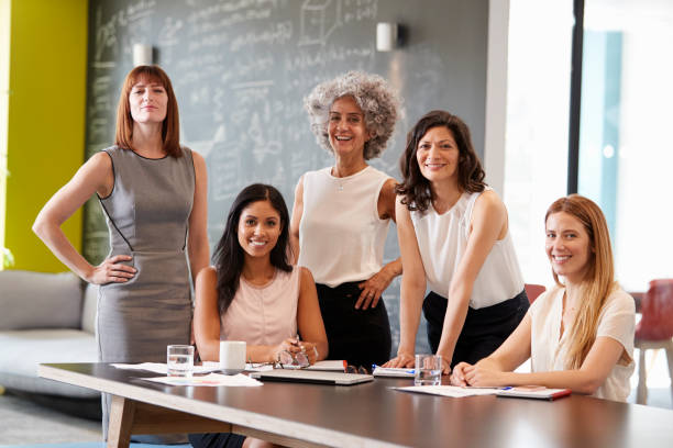 Five female colleagues at a work meeting smiling to camera Five female colleagues at a work meeting smiling to camera only women stock pictures, royalty-free photos & images