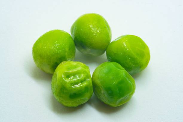 Five green peas on white background macro studio closeup stock photo