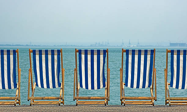 Five striped beach chairs overlooking the sea stock photo