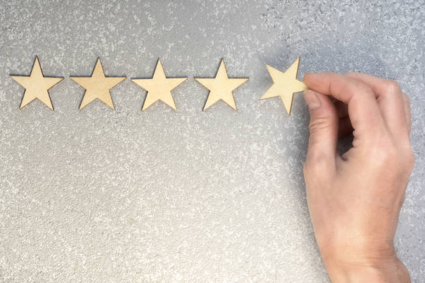 vijf houten sterren en hand om de laatste te verhogen top rating op een zilveren achtergrond, uitzicht met kopie ruimte - luxe hotel stockfoto's en -beelden