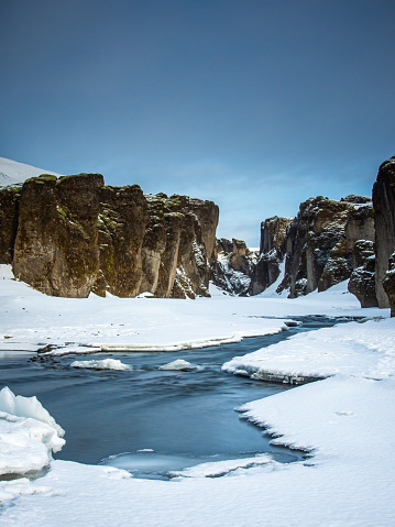 The river Fjaðrá running under ice and snow through Fjaðrárgljúfur, a canyon in south-east Iceland.