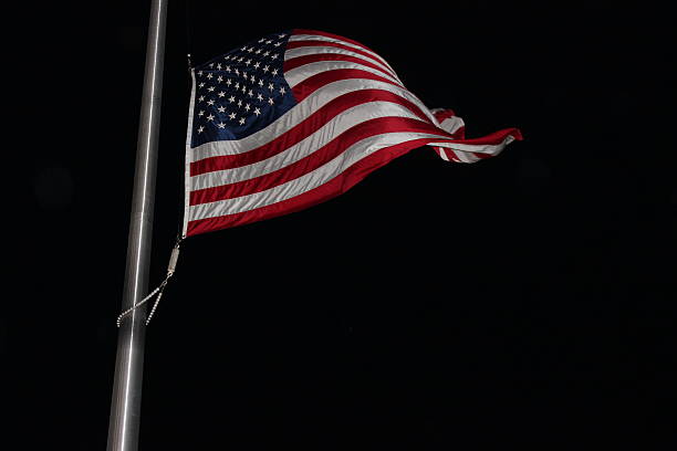 US Flag in the Wind at Night US Flag shot at night with flash while it was at half-mast. flag at half staff stock pictures, royalty-free photos & images
