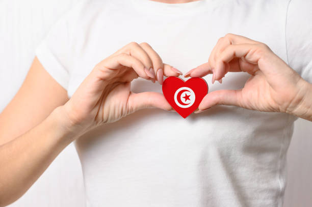 flag of Tunisia Love Tunisia. The girl holds a heart in the form of the flag of Tunisia on her chest. Tunisian concept of patriotism tunisia woman stock pictures, royalty-free photos & images