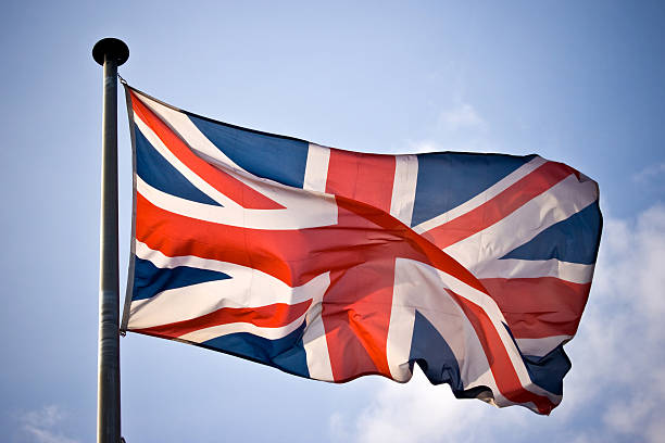 UK flag waving in sunny blue skies stock photo