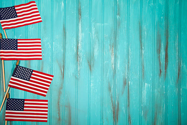 USA flags make left border. Blue wooden background. Happy Independence Day America!  Four USA flags form a left side border with copyspace to right. Teal blue wooden beadboard background with grunge painted effects.  Memorial Day, July 4th, Veteran's Day, Labor Day, Flag Day concepts.  American pride and patriotism. memorial day background stock pictures, royalty-free photos & images