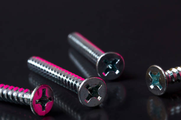 Flat head wood screws with colored reflections on black background stock photo