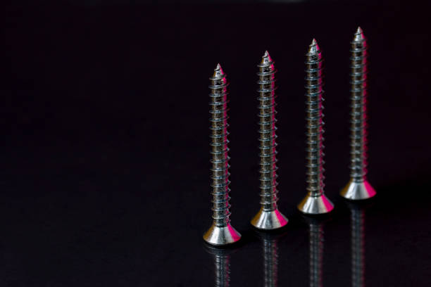 Flat head wood screws with colored reflections on black background stock photo