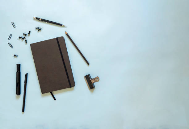 Flat lay of black stationery with a notebook in blue background stock photo