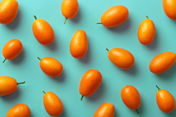 Flat lay pattern of fresh kumquats on a colorful background. Top view Flat lay pattern of fresh kumquats on a colorful background. Top view kumquat stock pictures, royalty-free photos & images