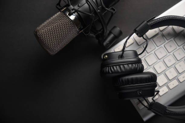 flat lay, microphone studio avec casque professionnel sur un clavier pc. noir sur un fond noir. podcasts, radio, flux, blogs, travail avec le son, enregistrement de pistes - podcast photos et images de collection
