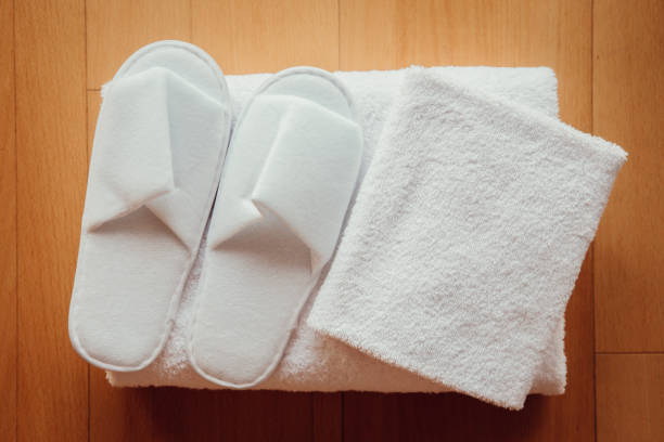 Flat lay view of fresh clean soft white hotel towels and disposable pair of slippers. stock photo