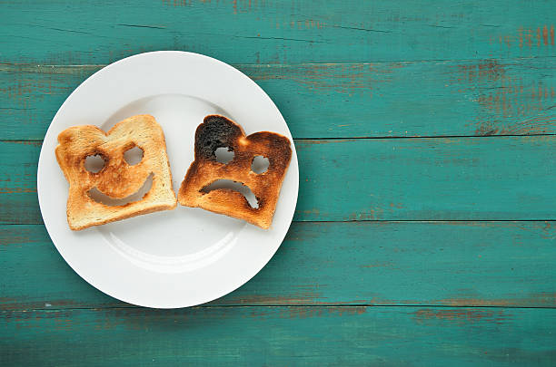 Flat lay view of two slices of toasted bread Flat lay view of two slices of toasted bread in a white plate. One is burned and one is well done. Relationship lifestyle concept. copy space toasted food stock pictures, royalty-free photos & images