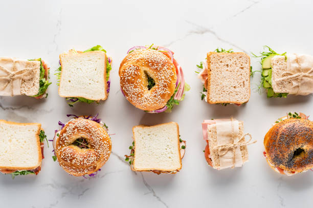 plano yacía con sándwiches frescos y bagels en la superficie blanca de mármol - sandwich fotografías e imágenes de stock