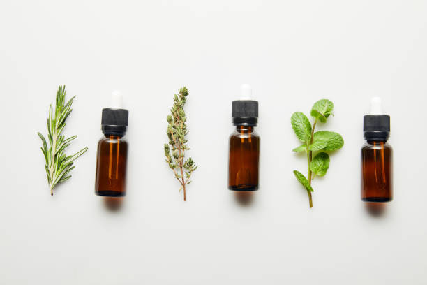 Flat lay with herbs and bottles with essential oil on white background Flat lay with herbs and bottles with essential oil on white background essential oil stock pictures, royalty-free photos & images