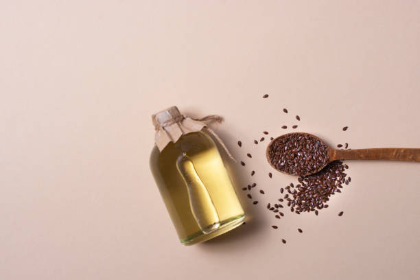 Flax seeds and a bottle of linseed oil on a beige background. Free space for an inscription. stock photo