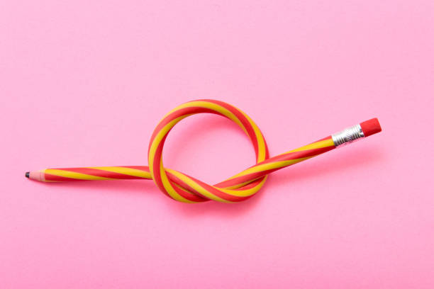 Flexible pencil on a pink background. Bent pencils two-color stock photo
