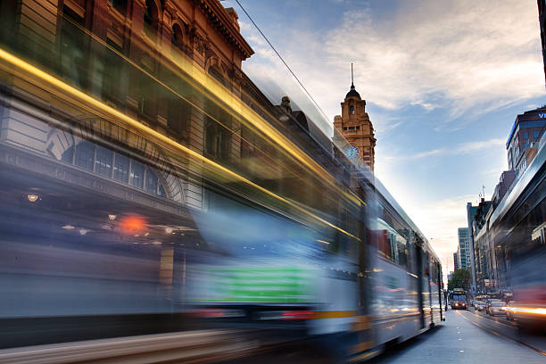 Flinders Street Tram passing through Flinders Street past Flinders Street Station on sunset melbourne street stock pictures, royalty-free photos & images