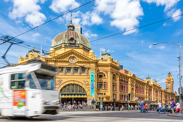 Flinders Street Station and Tram in Melbourne, Australia Flinders street station and tram in Melbourne, Australia on a nice sunny day. The tram is moving and people are walking at the busy intersection in the background. melbourne street stock pictures, royalty-free photos & images