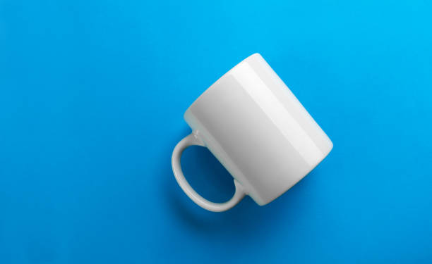 Flipped white mug on blue background Flipped white mug on blue background - mug template mug stock pictures, royalty-free photos & images