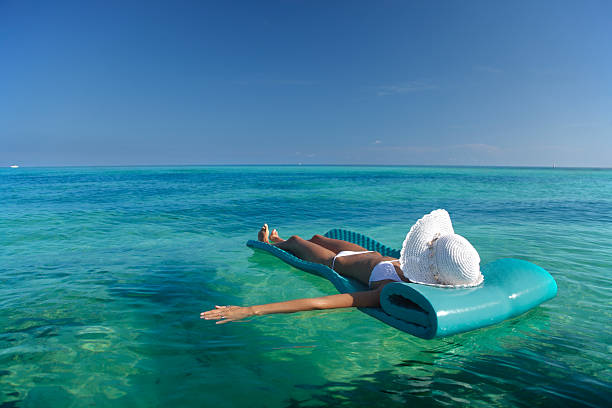 floating in the ocean woman floating on a raft in the water at a tropical beach inflatable raft stock pictures, royalty-free photos & images