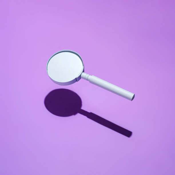 Floating magnifying glass with drop shadow on purple stock photo