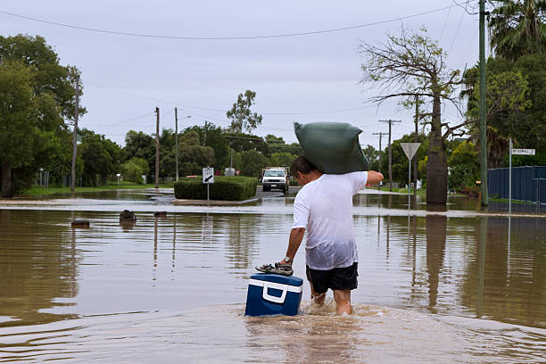 Flood Waters A man leaving his home walking through flood waters. flooding stock pictures, royalty-free photos & images