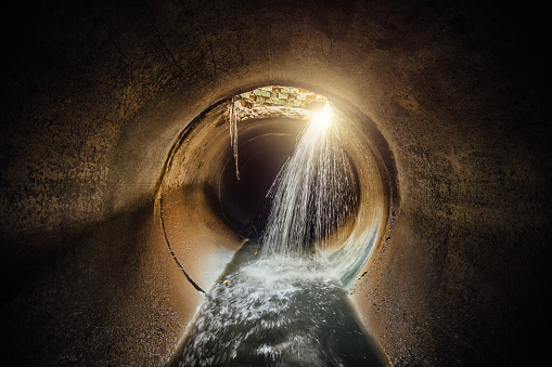 Flooded vaulted sewer tunnel with water reflection.