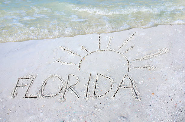 Florida sun drawn in sand on beach with a wave stock photo