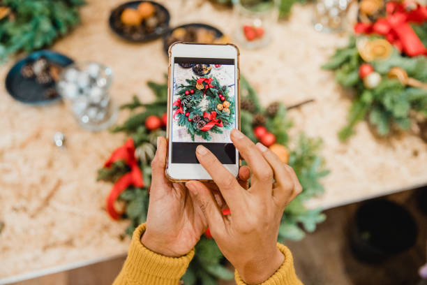 florist creating social media content - smartphone christmas imagens e fotografias de stock