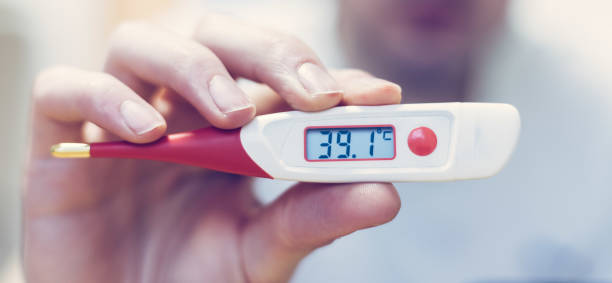 Flu and corona concept: Man is holding a fever thermometer in his hand, close up stock photo