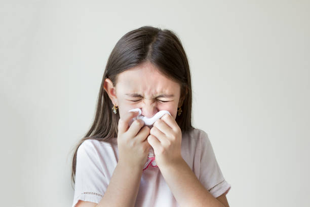 Flu concept - Upset and sick child blowing his nose with flu symptoms coughing at home, Allergic girl, flu season. Girl with cold rhinitis, cold stock photo
