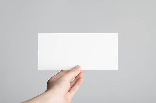 Male hands holding a blank flyer on a gray background.