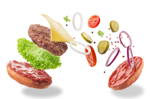 Flying burger ingredients. Isolated on a white background. Bun, salad, cheese, cutlet, onion, cucumber, ketchup, pepper.