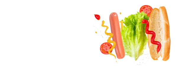 Flying ingredients for delicious hot dog on white background. Levitating sausage, tomatoes and lettuce. stock photo