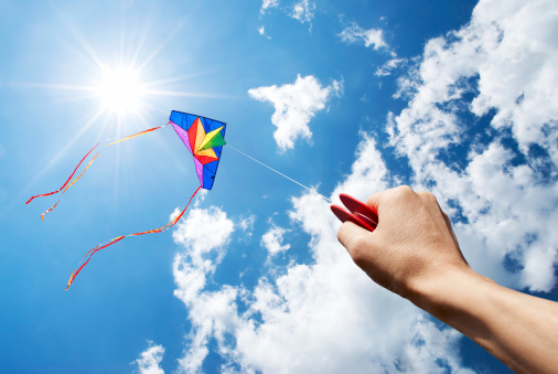 kite flying in a beautiful sky with sun and clouds