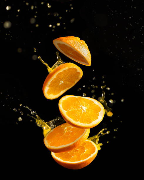 fliegende orange auf schwarzem hintergrund mit splaches, vertikale ausrichtung - orange frucht stock-fotos und bilder
